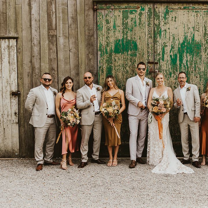 Wedding party with the groomsmen all in sunglasses and light suits and the bridesmaids in mismatched dresses