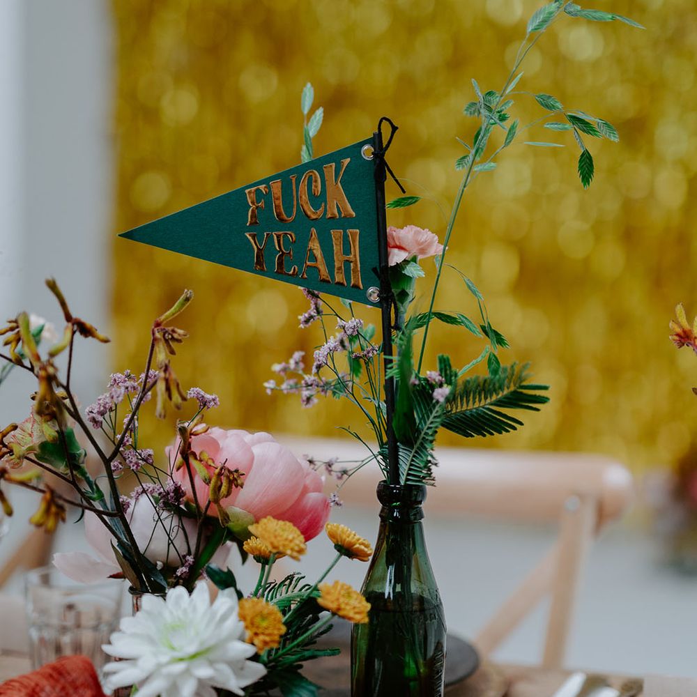Green & gold fabric sign in thrifted vases on wooden tables with retro feel