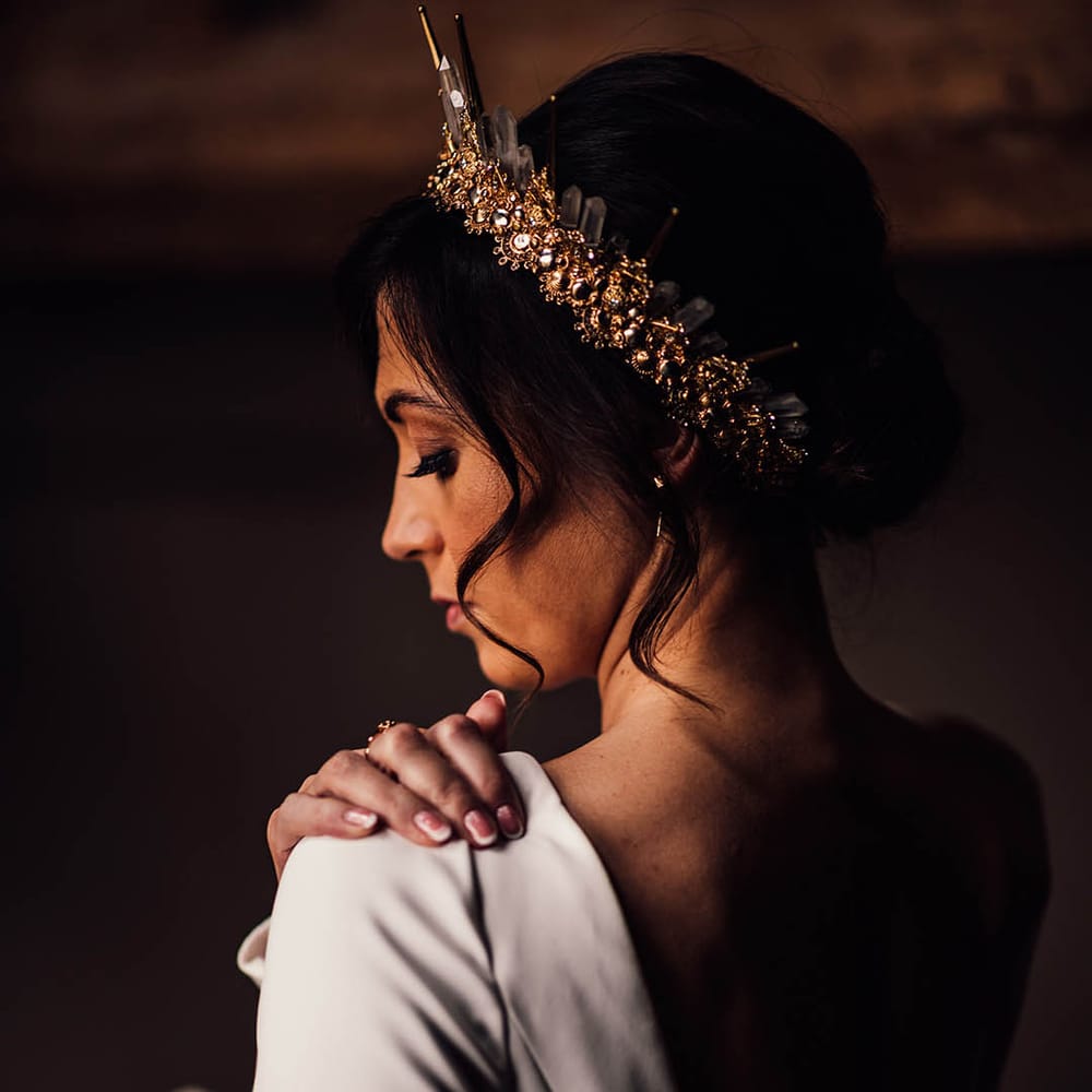 Bride with white French tip wedding nails in a long sleeve wedding dress with updo hairstyle complete with gold crown 