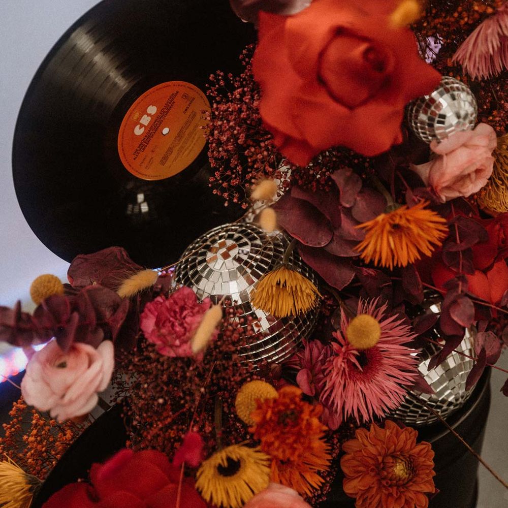 Vinyl wedding arch with disco ball wedding decor and pink, orange and red wedding florals 
