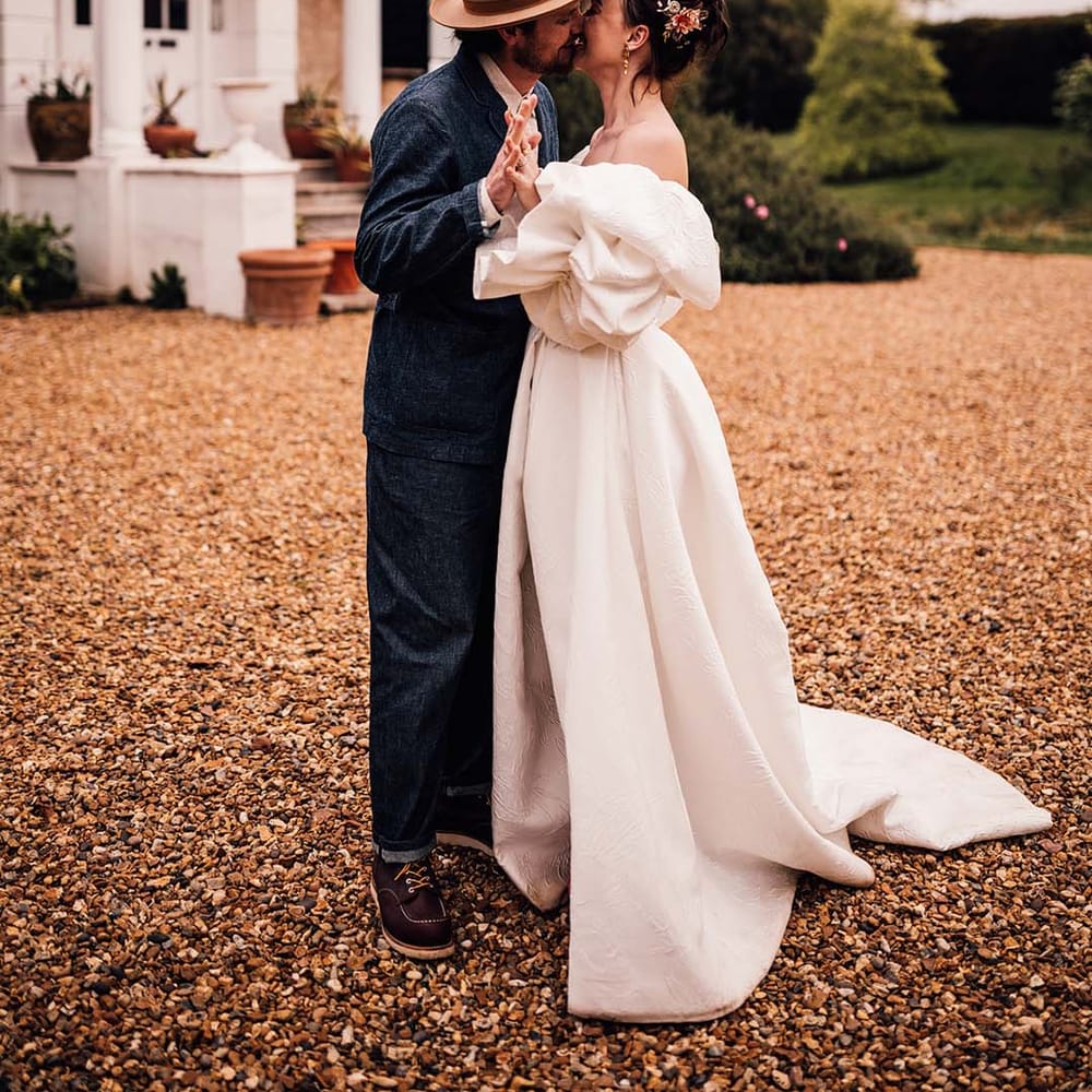 Bride in puff sleeve wedding dress by Jesus Peiro kissing the groom at Preston Court in Kent wedding 