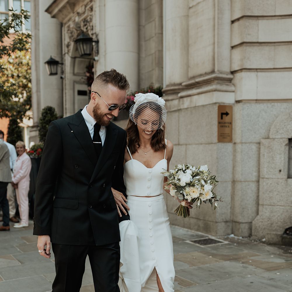 stylish Chelsea wedding with bride in skirt, top and headband and groom in a black suit 