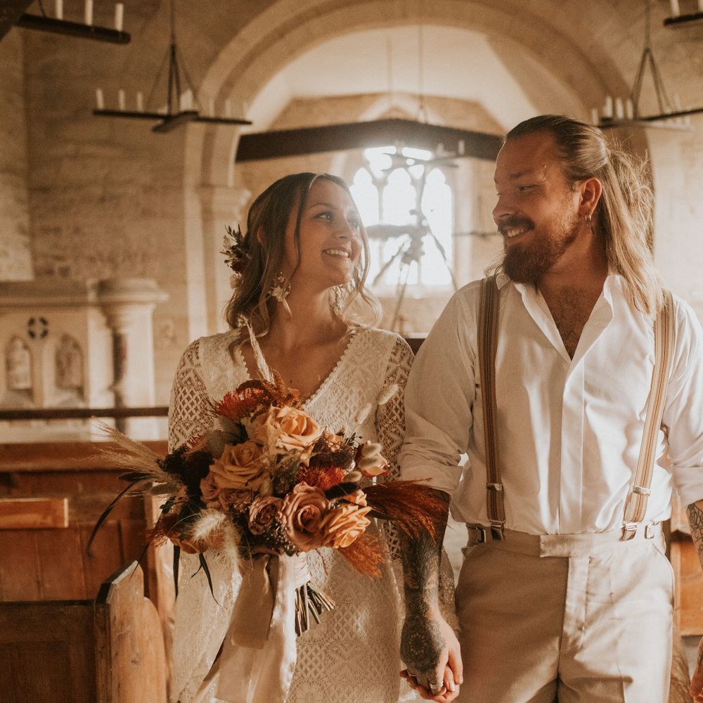 Bride & groom walk down the aisle with bride holding Autumnal bouquet 