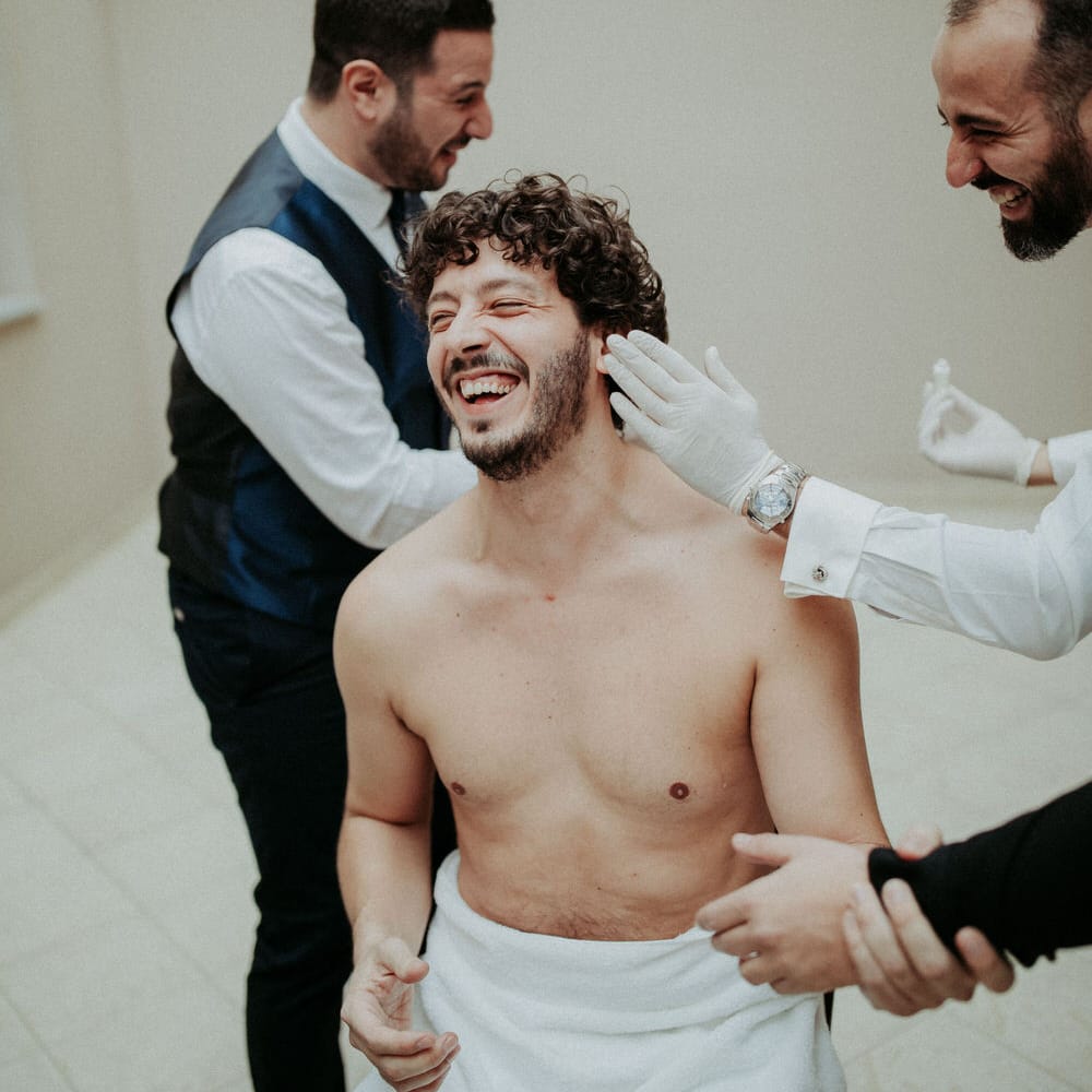The groom being assisted with getting ready