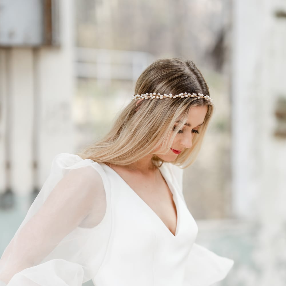 Bride in a fitted wedding dress with sheer blouson sleeves wearing a pearl halo headdress 