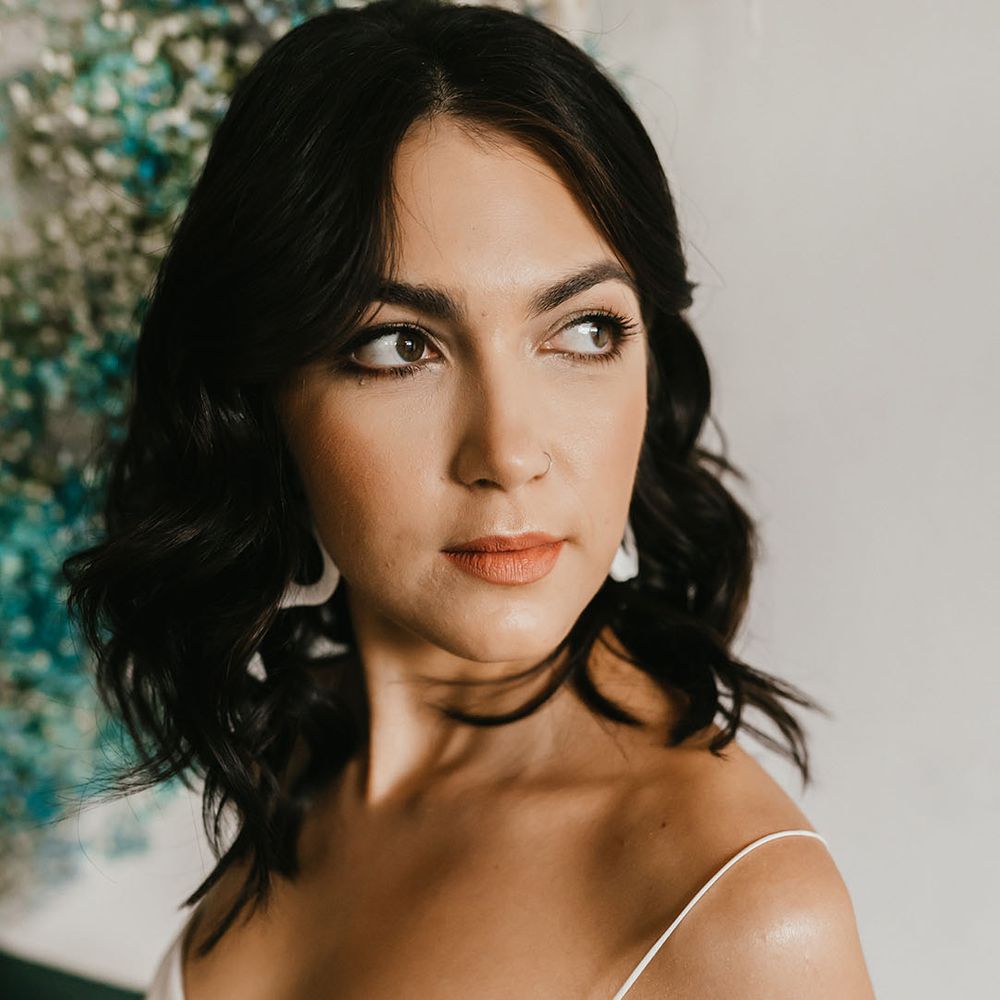 Beautiful bride with shoulder length wavy hair and natural wedding makeup wearing dangly earrings 