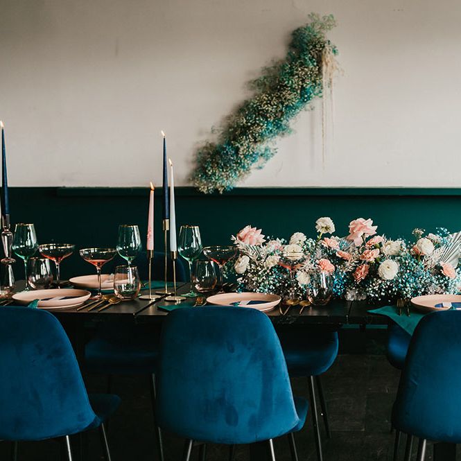Stylish wedding reception decor with teal velvet chairs, gypsophila flower clouds and taper candles 