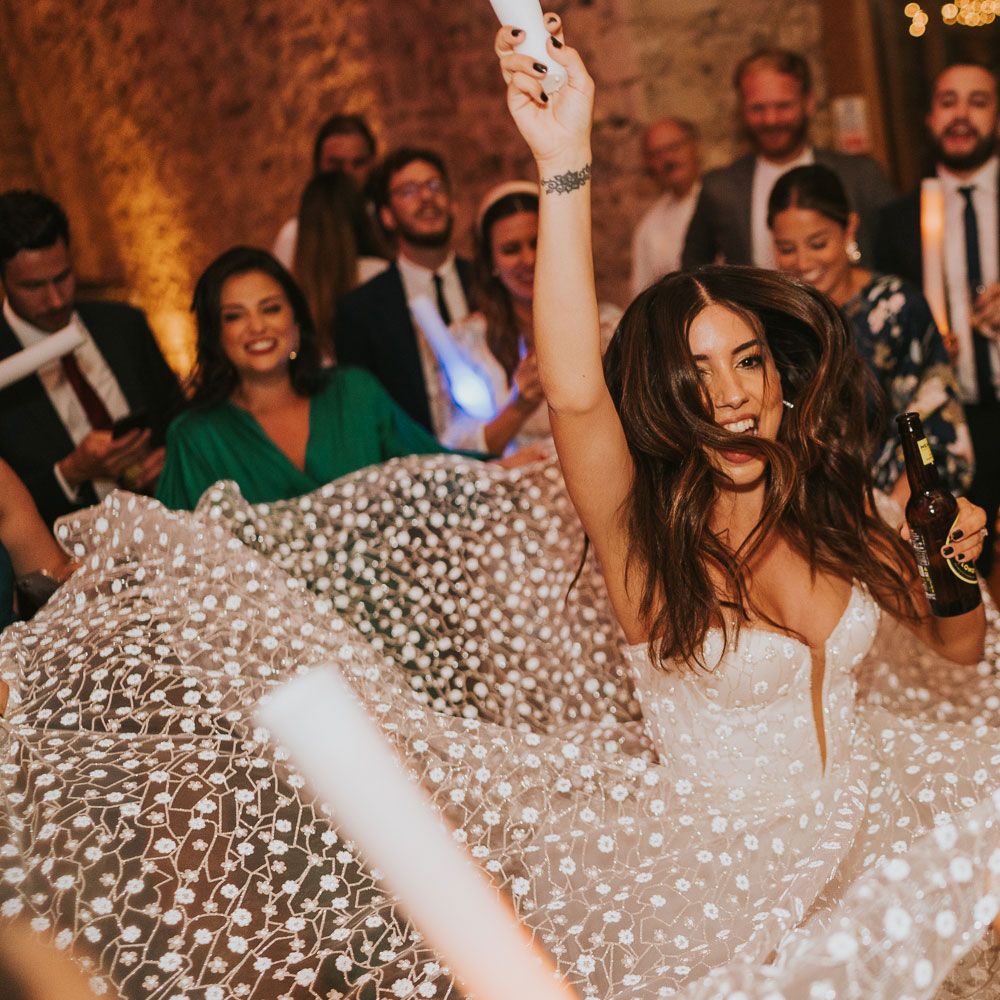 Bride in white applique Pronovias wedding dress and Jimmy Choo wedding shoes spins in centre of circle of wedding guess during evening wedding reception at Notley Abbey wedding