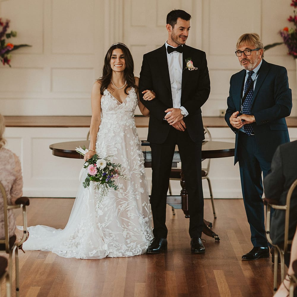 Bride & groom link arms at the front of the room as they leave their ceremony