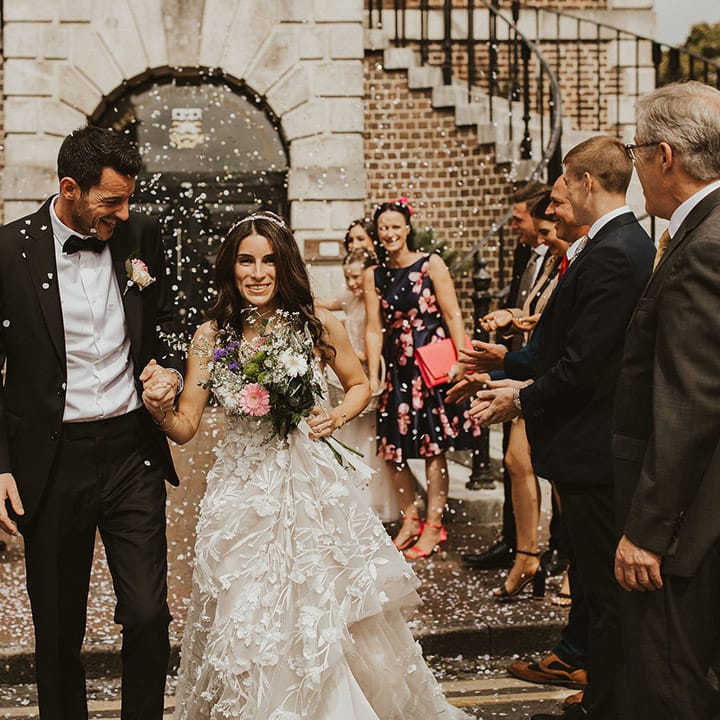 Bride & groom walk through white confetti on their wedding day