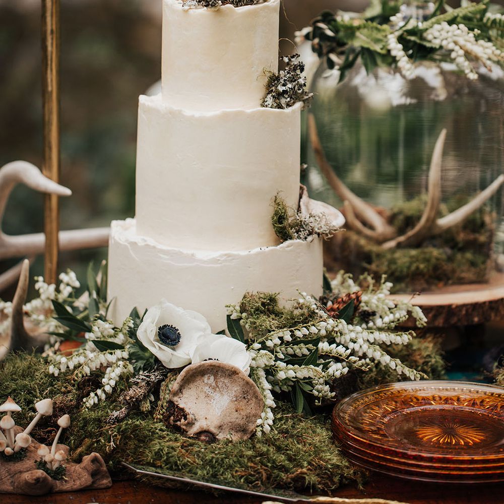 three tier buttercream wedding cake decorated in foliage, moss and anemones 