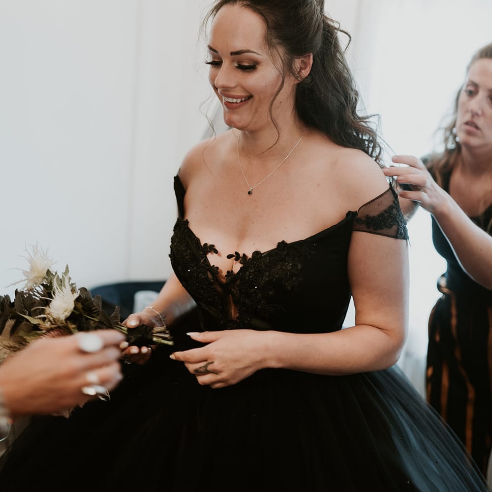 Bride has her black bridal gown done up on the morning of her wedding