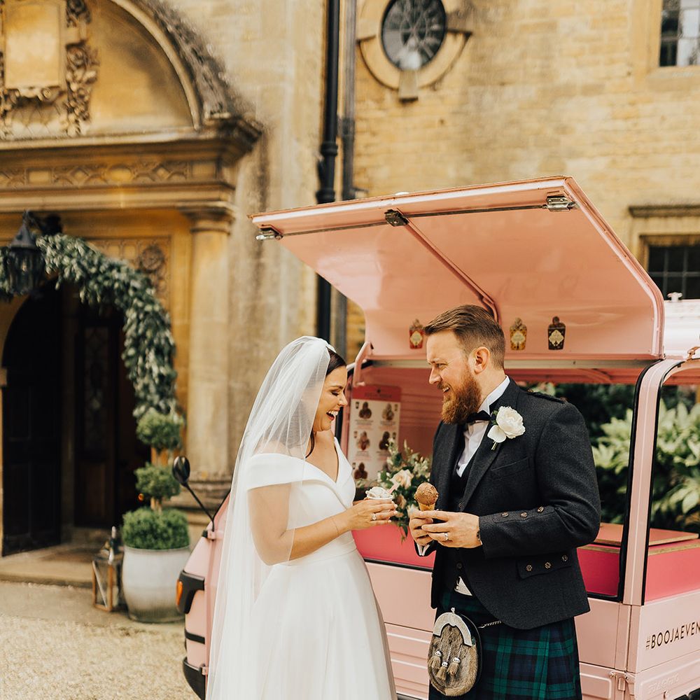 Groom in a tartan kilt holding  and bride in an off the shoulder Suzanne Neville wedding dress eating dairy free vegan ice cream from a truck