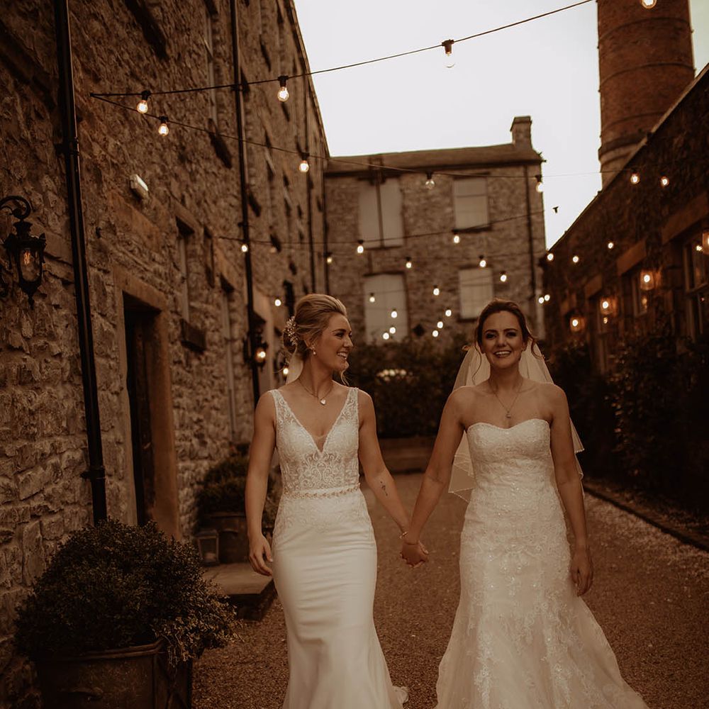 Holmes Mill Lesbian wedding with two bries in a strapless lace wedding dress and fitted fishtail wedding dress holding hands 