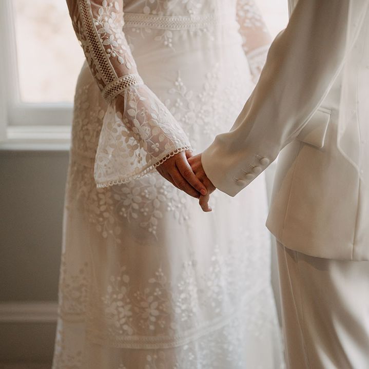 Brides hold hands on their wedding day during ceremony