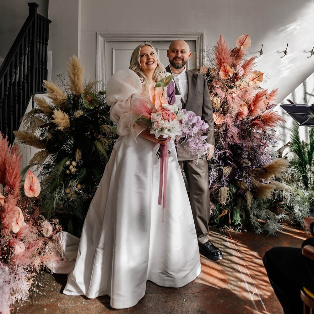 Modern stylish London wedding with dried and fresh flower column arrangements, bride in a princess wedding dress and groom in a double breasted jacket 