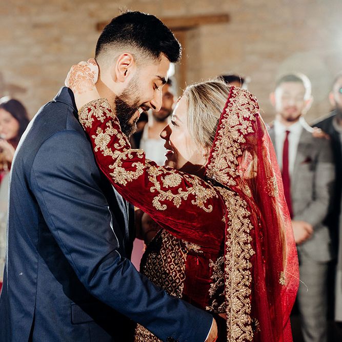 Bride wears crushed velvet saree complete with gold embellishment dances with her groom wearing blue three piece suit