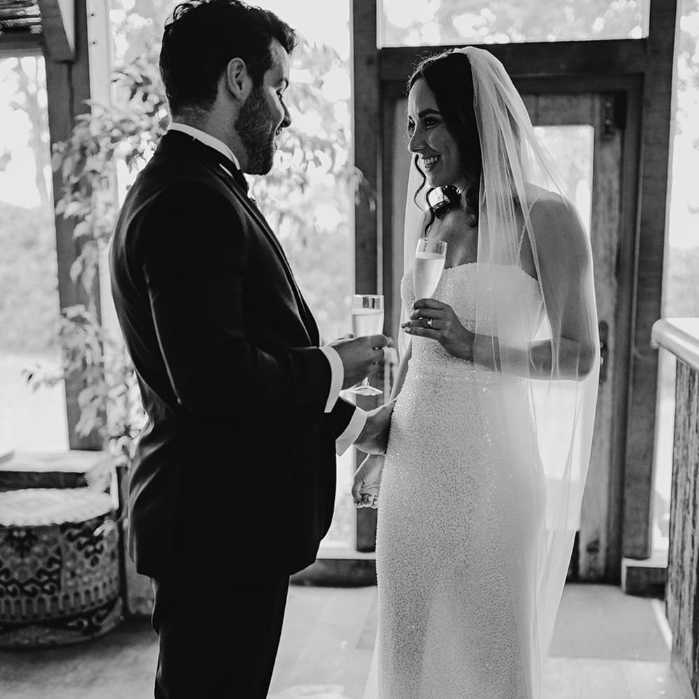 The bride and groom share a glass of champagne together to celebrate their wedding 