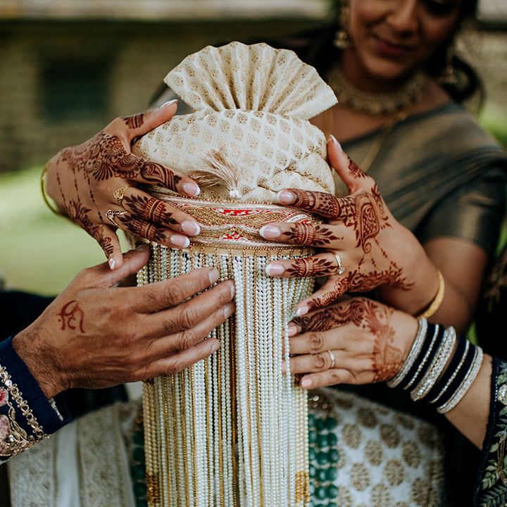 Family members cover grooms face with beads during multicultural wedding outdoors at The Tithe Barn Bolton Abbey