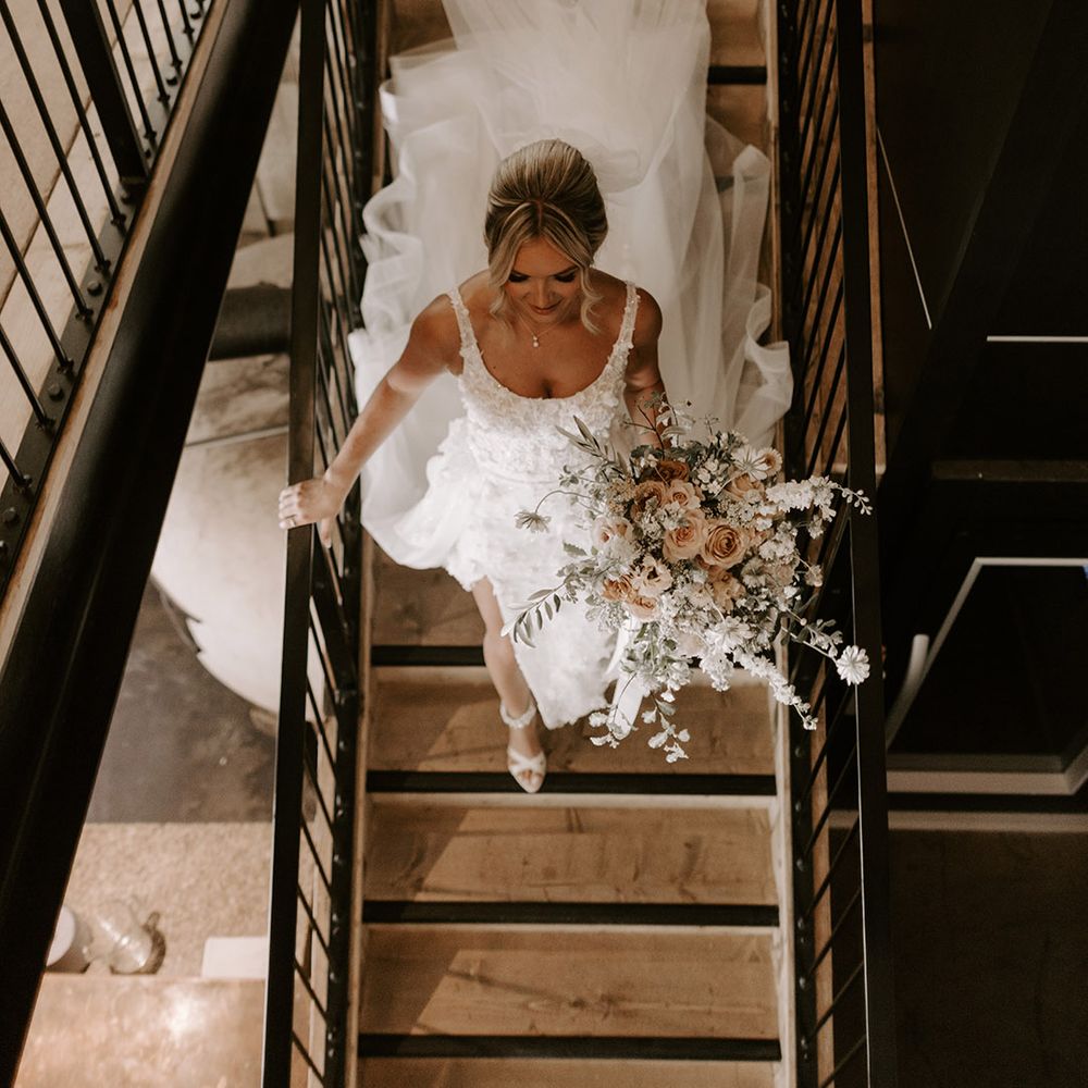 Bride in cathedral length pearl wedding veil and princess skirt wedding dress walking down the stairs on the way to the wedding 