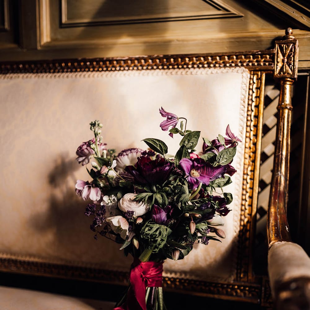 Purple and white wedding bouquet tied with dark red ribbon 