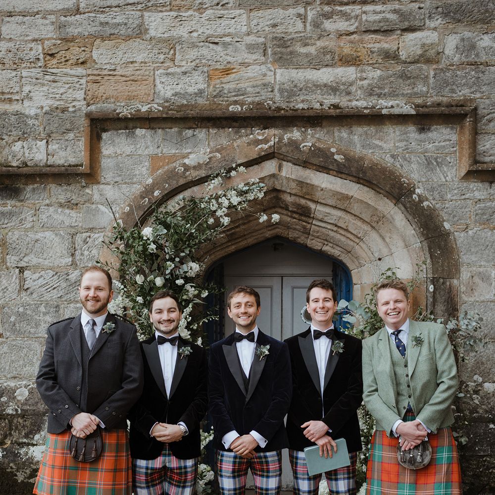 Groom and groomsmen in tartan trousers or kilts for the wedding 