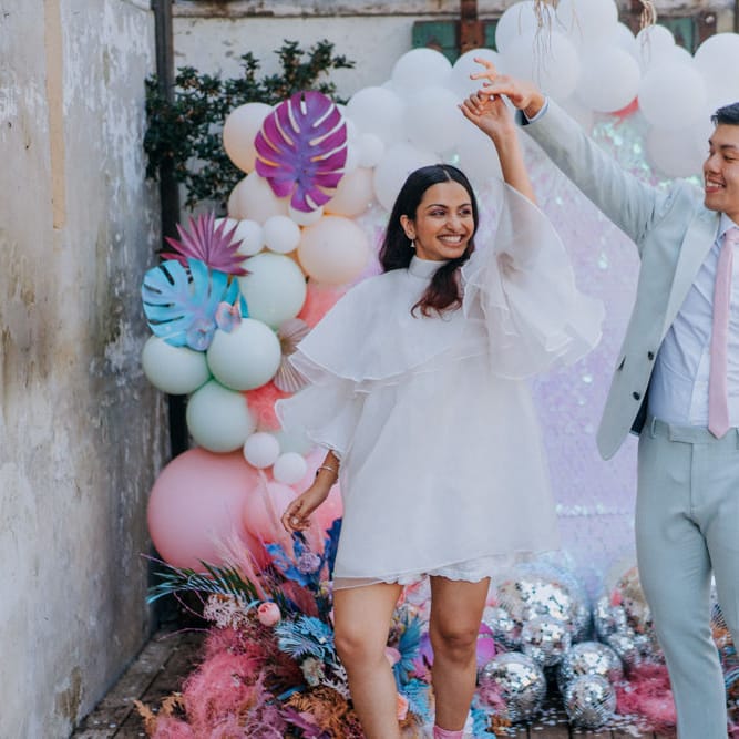 Bride and groom dancing in front of their sequin, glitter balls and balloon wedding altar 
