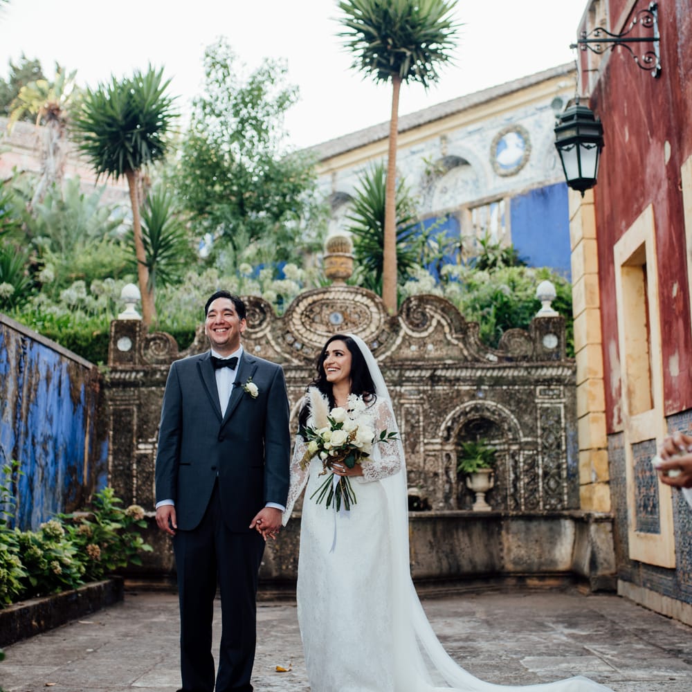 Bride & groom stand outdoors as bride holds classic white bouquet with pampas grass