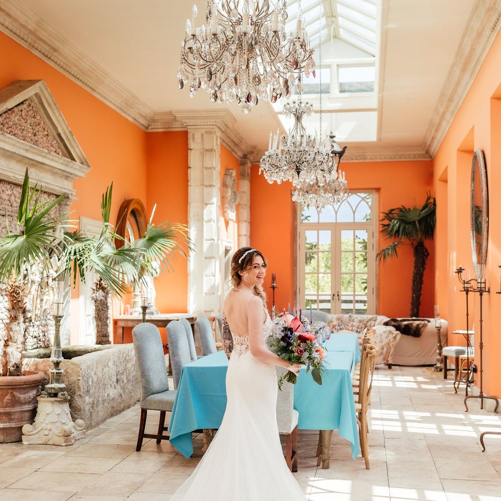 Bride stands within bright orange room with pale blue table in the background