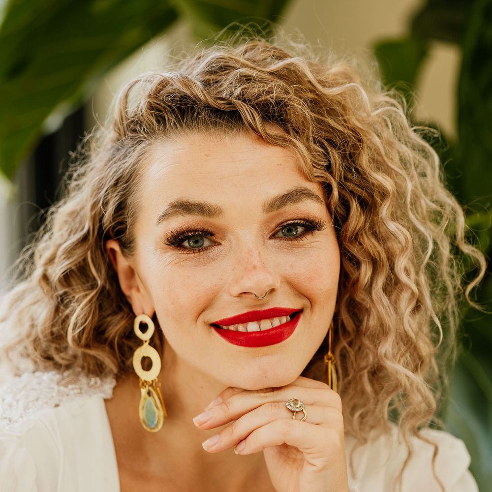 Beautiful blonde naturally curly haired bride with bright red lipstick and brown shimmering eyeshadow at fiesta theme wedding 