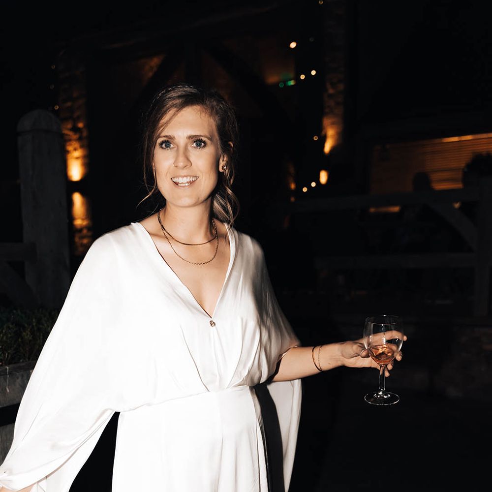Brown haired bride carries wine glass during wedding reception