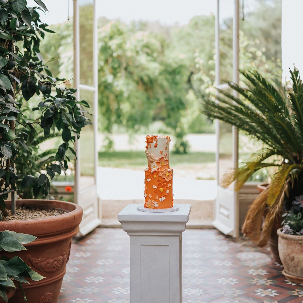 Two tier orange ombre buttercream wedding cake with petal decor in and orangery
