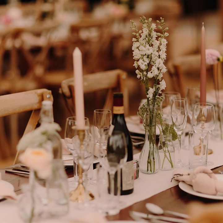 Pink candles and blush flowers decorated wooden tables