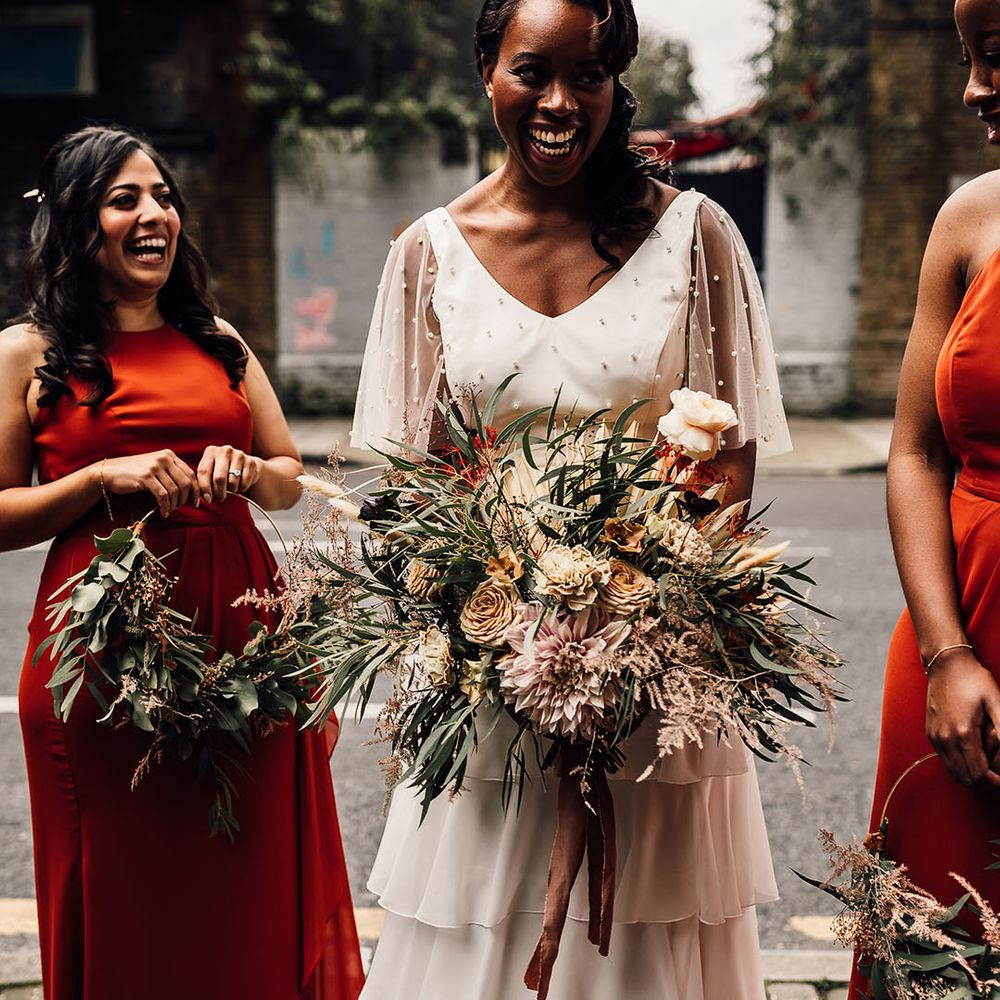 Beautiful Black bride in a bridal separates with layered skirt and pearl top holding an oversized wedding bouquet