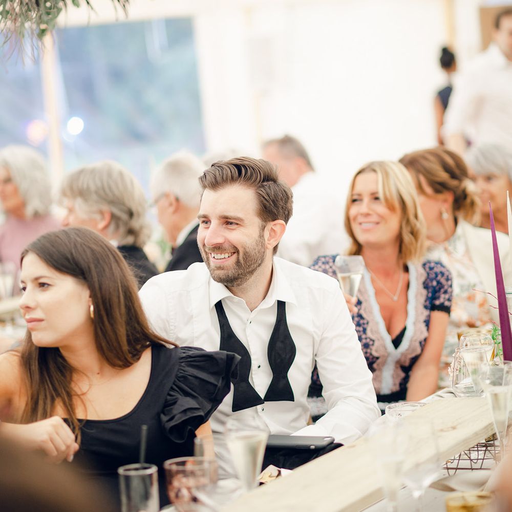 Guests enjoy wedding speeches at marquee wedding