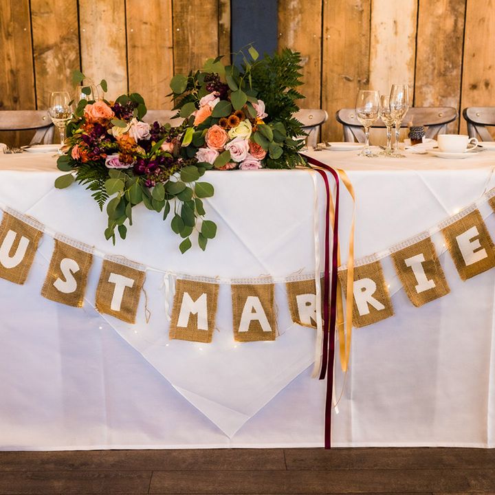 Woven 'Just Married' bunting across the top table with the bride's wedding bouquets