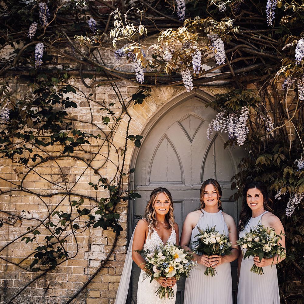 Bride in lace wedding dress with detachable tulle wings and bridesmaids in pleated halter neck grey dresses 