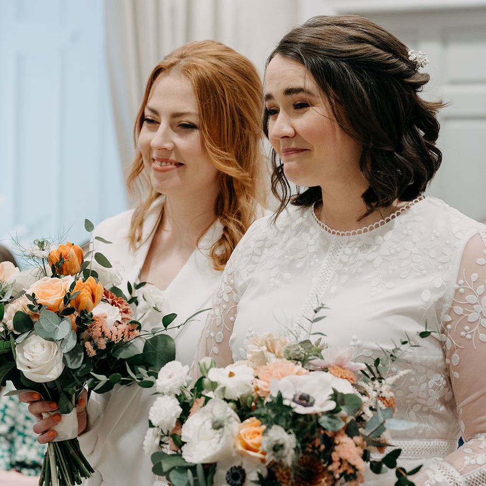 Brides look lovingly alongside one another during wedding ceremony