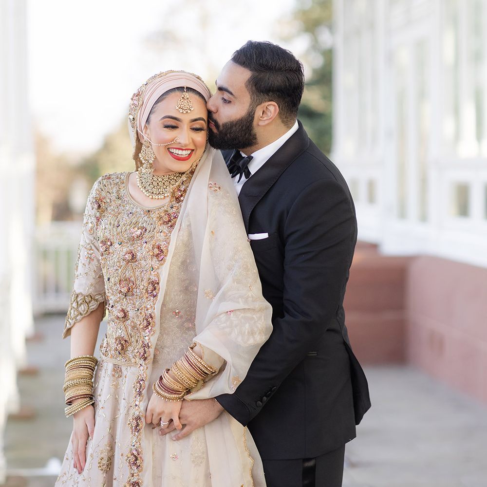 Groom wears black tie and kisses brides forehead after Walima 