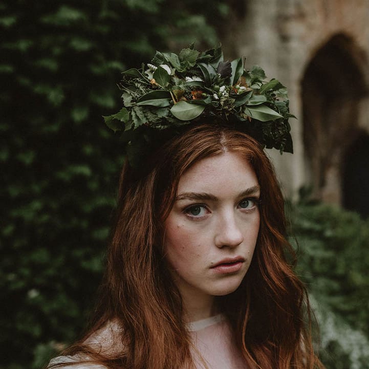 Bride with long wavy red hair and natural makeup wearing a green foliage flower crown 