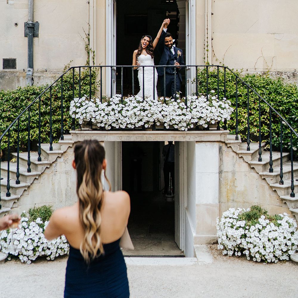 Bride & groom stand on balcony complete with white florals at Syon Park 
