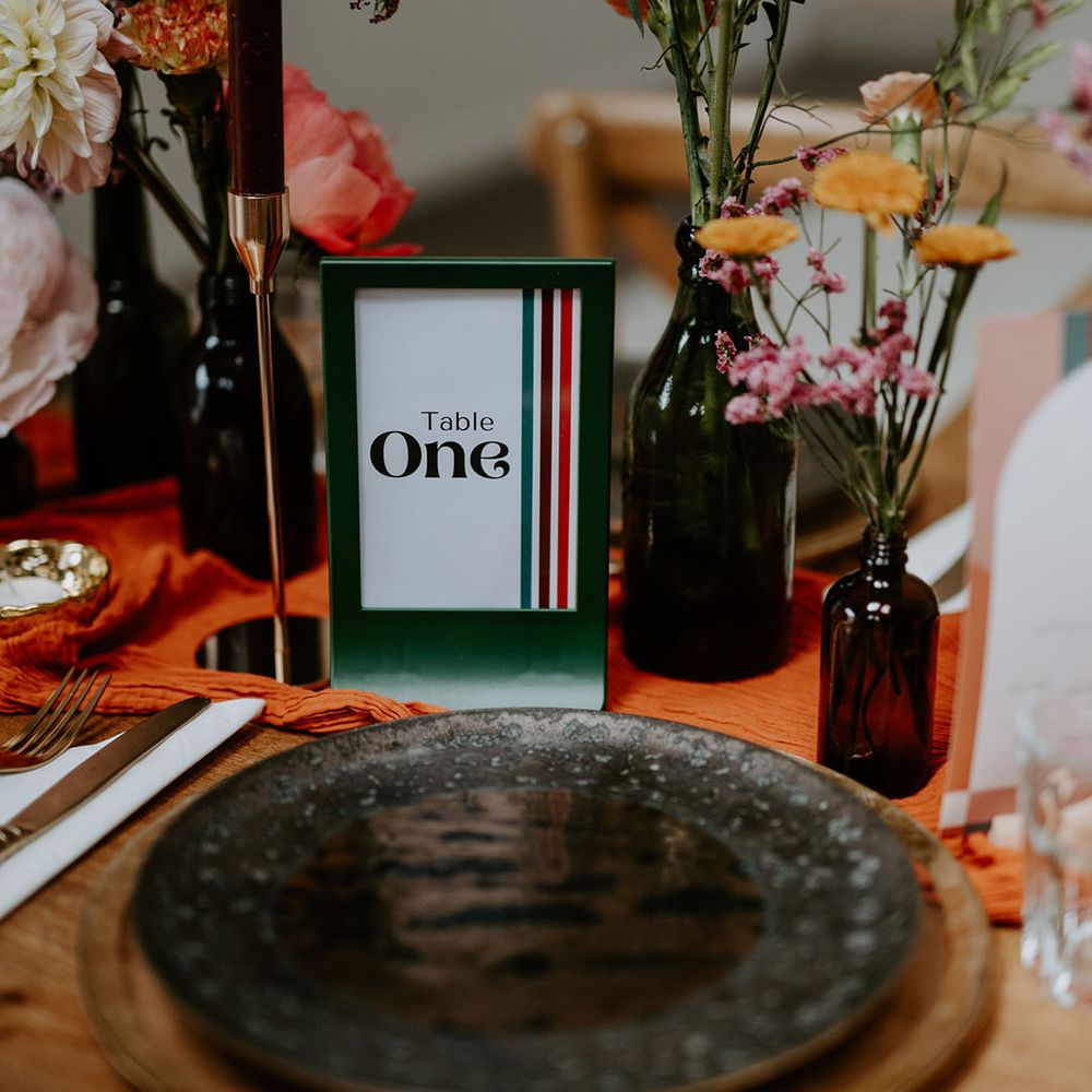 Retro styled table numbers complete with small floral centrepieces and orange table runner 