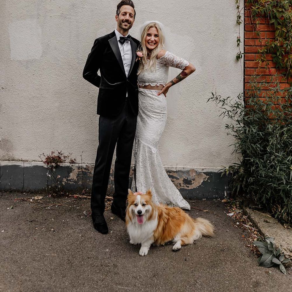Bride in boho two piece lace bridal outfit and groom in black tux with velvet look bow tie embracing and smiling