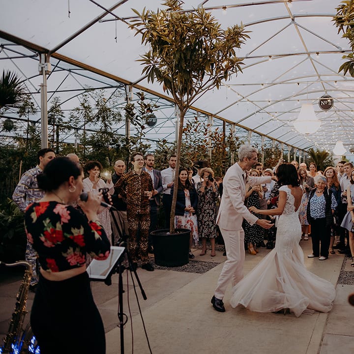 Bride and Groom having their first dance to a live singer while guests are watching