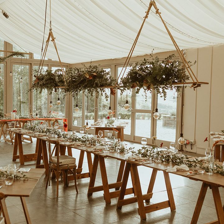 Trevenna Barns wedding venue with festoon lighting, hanging floral installations, and minimal wedding table setting 