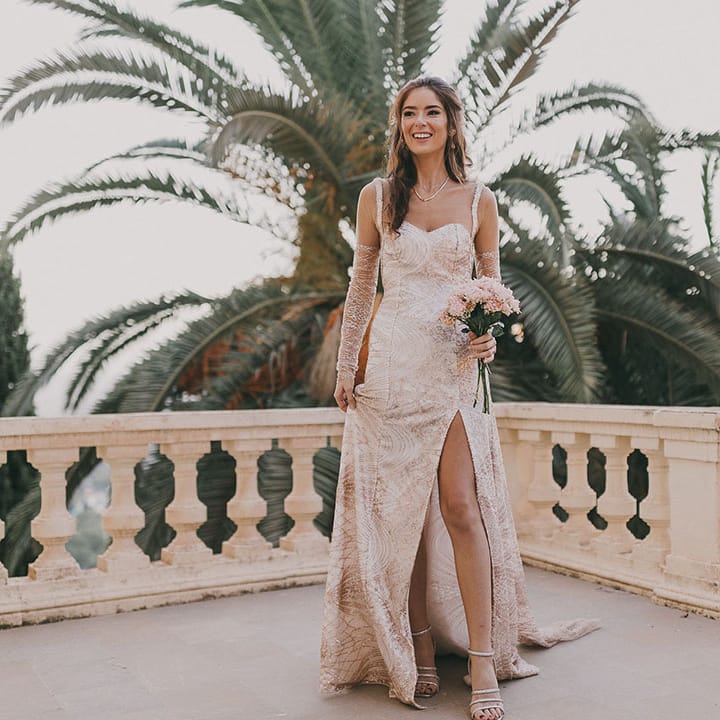 bride in a bespoke gold sparkly wedding dress with front slit and sheer long sleeves