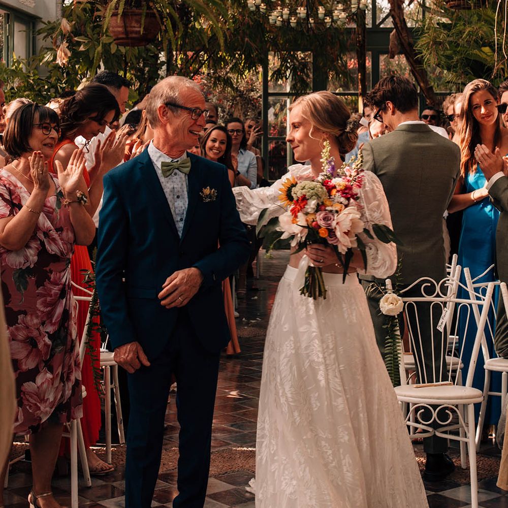 Bride in long skirt and crop top bridal separates hugging her father as she walks to the groom 