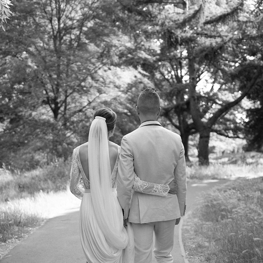 bride in a low back wedding dress with lace long sleeves embracing her groom 