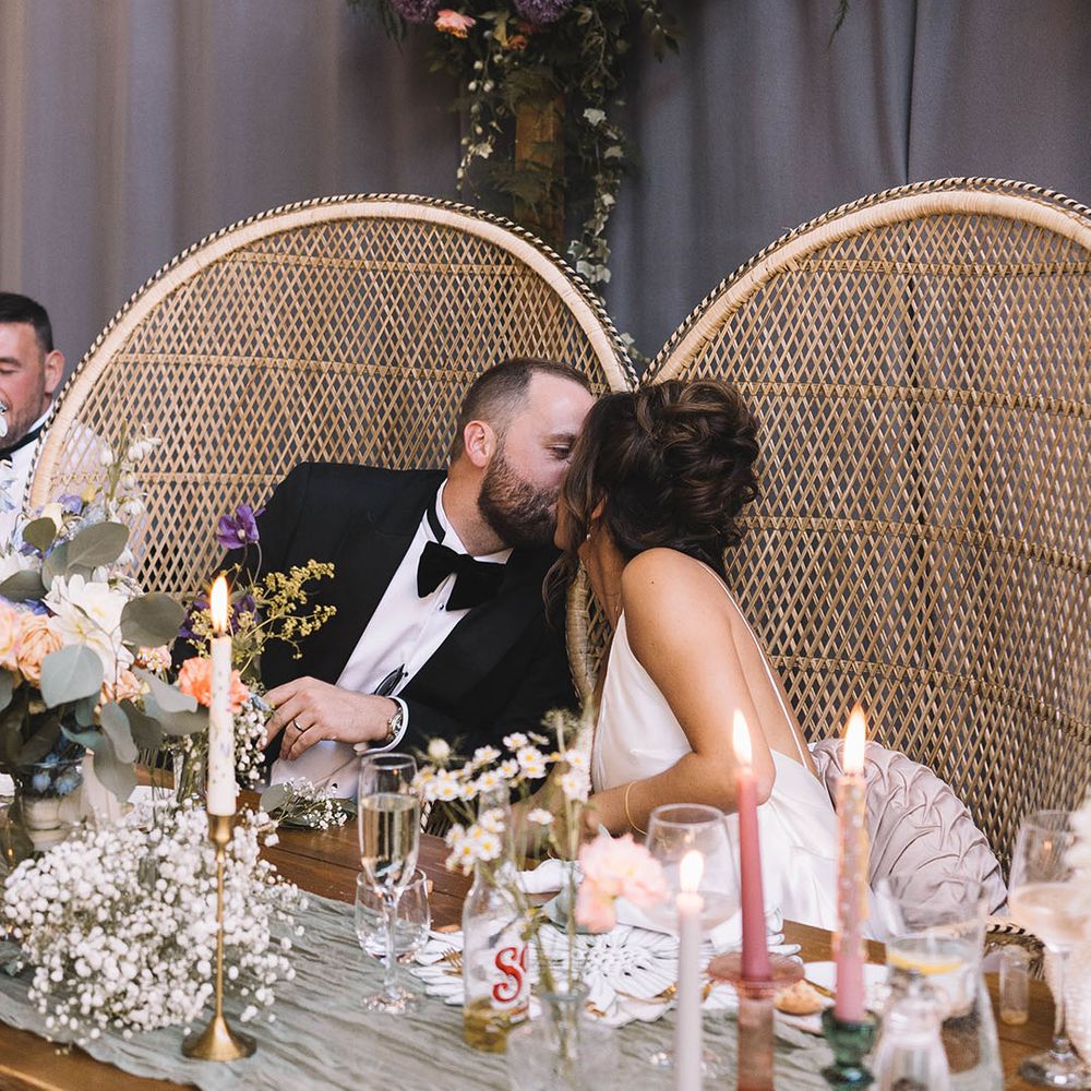 The bride and groom sit in peacock chairs and share a kiss at Bowers Mill Yorkshire wedding 