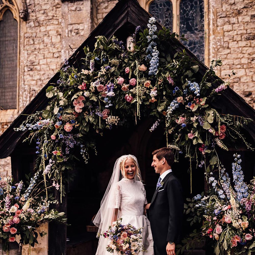 Bride and groom at church wedding decorated with blue flower arch 